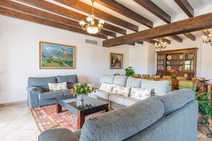 A living room with a sofa, coffee table, and a cabinet with decorative plates. - Rural Idyll Villa "El Palmeral" with Pool (Petra)