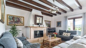 A living room with a fireplace, sofas, a TV, and a large window with a view.