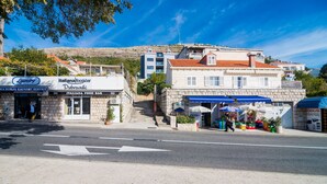 Vista de la calle con un servicio de lavandería, una barra de comida italiana y un puesto de mercado.