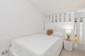 Une chambre à coucher avec un lit, une table de chevet, une lampe et un miroir.