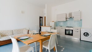 Una cocina moderna con comedor, sofá y lavadora.