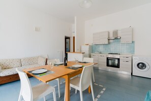 Una cocina moderna con comedor, sofá y lavadora.