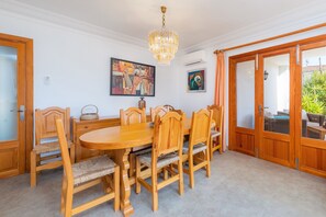 A dining room with a wooden table and chairs, a chandelier, and artwork on the walls.