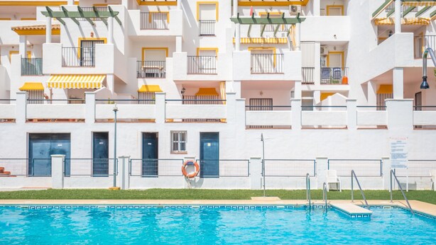 Ein mehrstöckiges Hotel mit Balkonen, einem Schwimmbecken und einem Rettungsring.