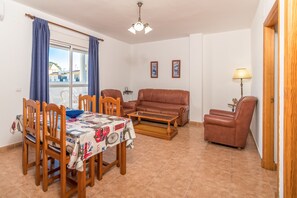 Un coin repas avec une table dressée pour quatre personnes, un canapé, une table basse et une lampe.