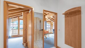 A room with wooden beams, a sliding door, a small table, and a chair. - Charming Apartment “Petrushof Rechenberg” with Mountain View, Wi-Fi, Balcony (Oberwössen)