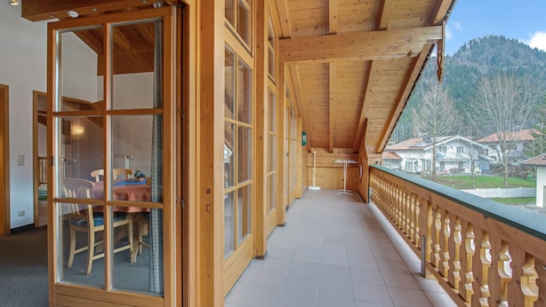 A wooden corridor with a view of houses and mountains. - Charming Apartment “Petrushof Rechenberg” with Mountain View, Wi-Fi, Balcony (Oberwössen)
