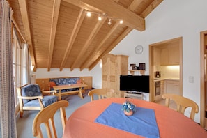 Une pièce chaleureuse avec un plafond en bois, un canapé, une table à manger et un téléviseur.