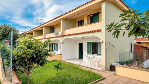A two-story house with a balcony, a small garden, and a satellite dish. - Charming Holiday Home Tanaunella appartamento 2 with Ventilators, Balcony, Terraces & Sea View; Parking Available, Pets Allowed (tanaunella)