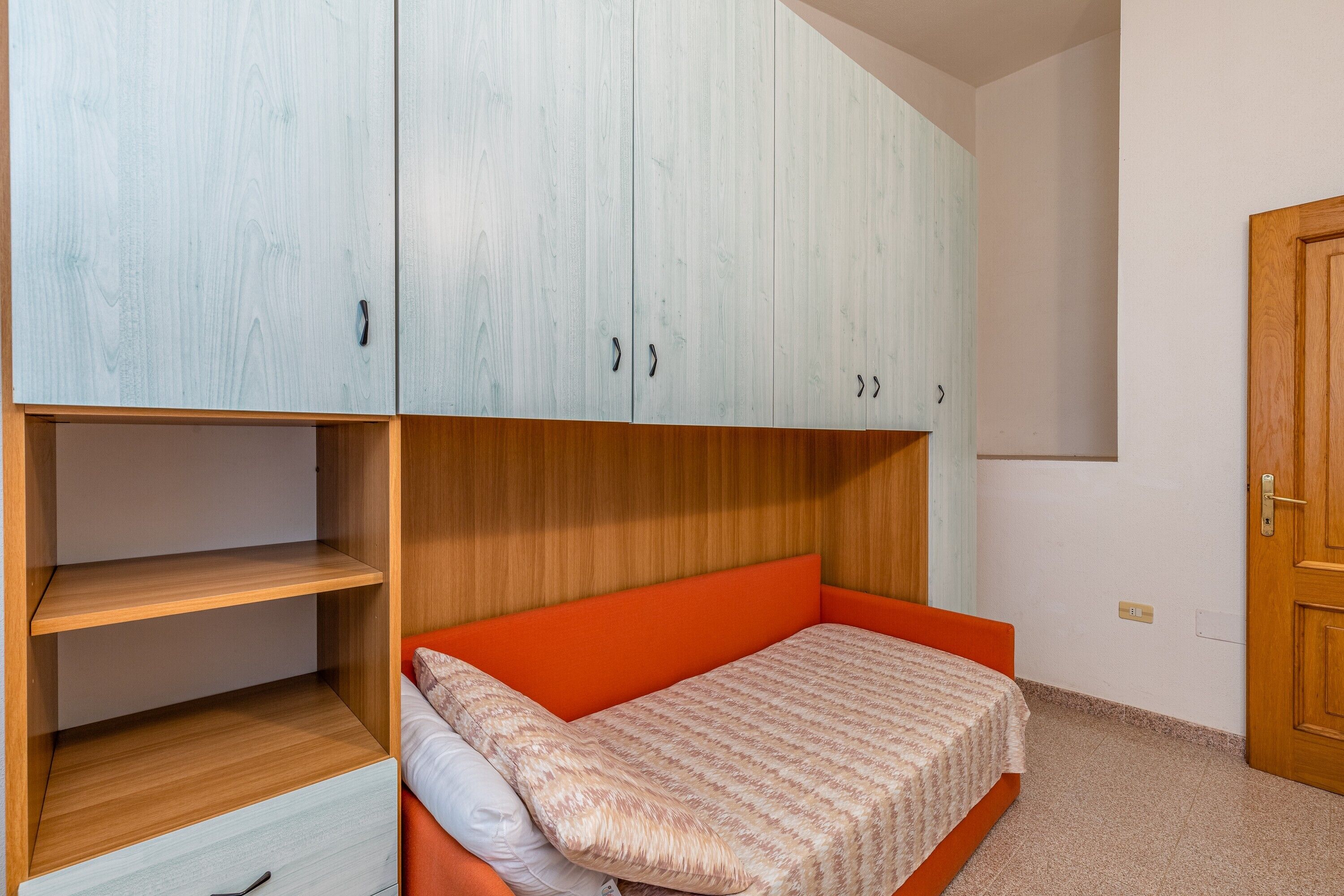 Un dormitorio con cama, armario y puerta.