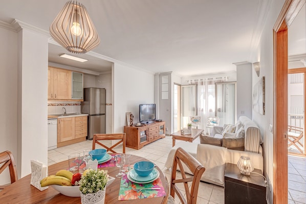 Uma sala de estar moderna com sofá, mesa de jantar e área de cozinha.