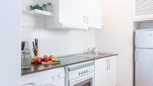 Eine Küche mit Waschmaschine, Backofen, Spüle und weißen Schränken.