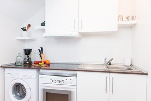 A modern kitchen with a washing machine, oven, and a sink.