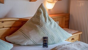 A wooden bed with a pillow, a bedside lamp, and a small bedside table.