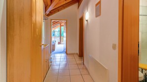 A hallway with wooden doors, a tiled floor, and a wooden ceiling.