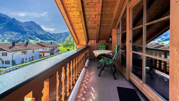 A wooden balcony with a view of houses and mountains.