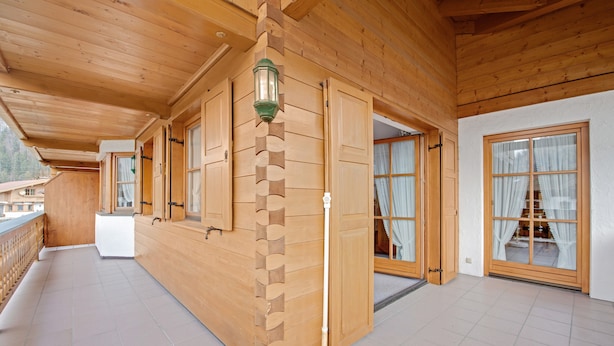 A wooden interior with a reception desk, a wooden wall with a unique pattern, and a large window with curtains. - Apartment “Petrushof Ferienwohnung Taubensee” with Mountain View, Wi-Fi, Balcony (Oberwössen)