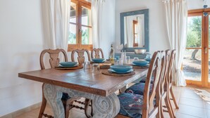 Een eethoek met een houten tafel, stoelen en blauwe kommen.