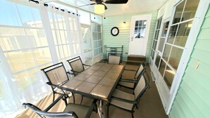 Un patio coperto con tavolo e sedie, una ventola a soffitto e un orologio appeso al muro.