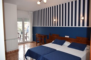 Habitación de hotel con una cama grande, un escritorio y una silla. Se ve una ventana con vistas al exterior.