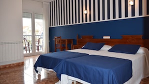A hotel room with two beds, a wooden headboard, a small table, and a chair.