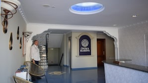 A reception area with a sign reading "OSTRA MARINA," a reception desk, and a staircase leading to another floor.