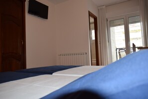 A bedroom with a bed, a wooden wardrobe, a radiator, and a sliding glass door leading to a balcony. - Hotel VIDA Ostra Marina (Sanxenxo)