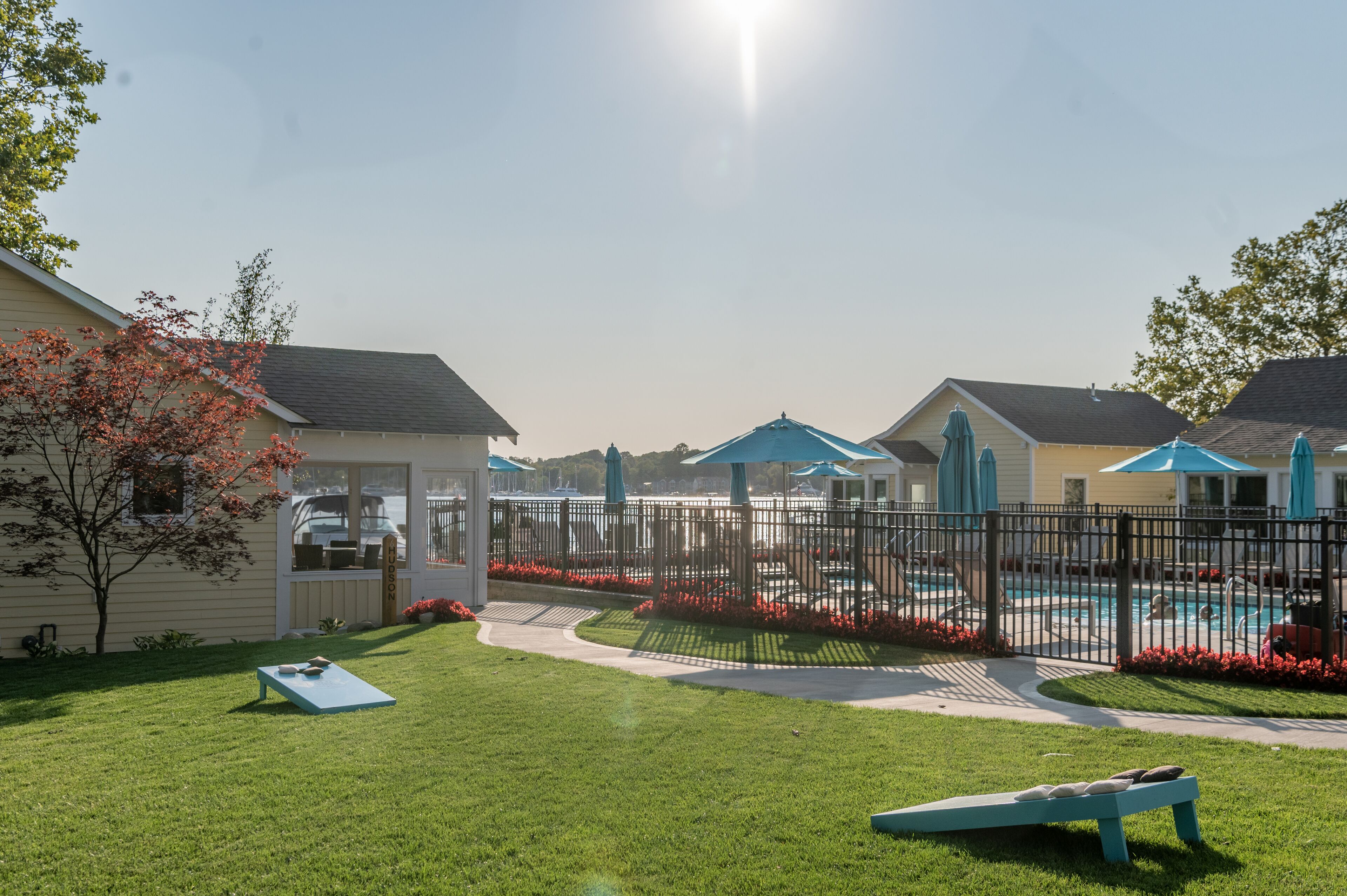 A fenced backyard with a swimming pool, a lounge chair, and a small play area.