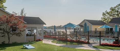 A fenced backyard with a swimming pool, a lounge chair, and a small play area.