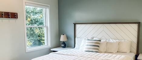 Quarto com uma cama grande, mesa de cabeceira, janela e ventilador de teto.
