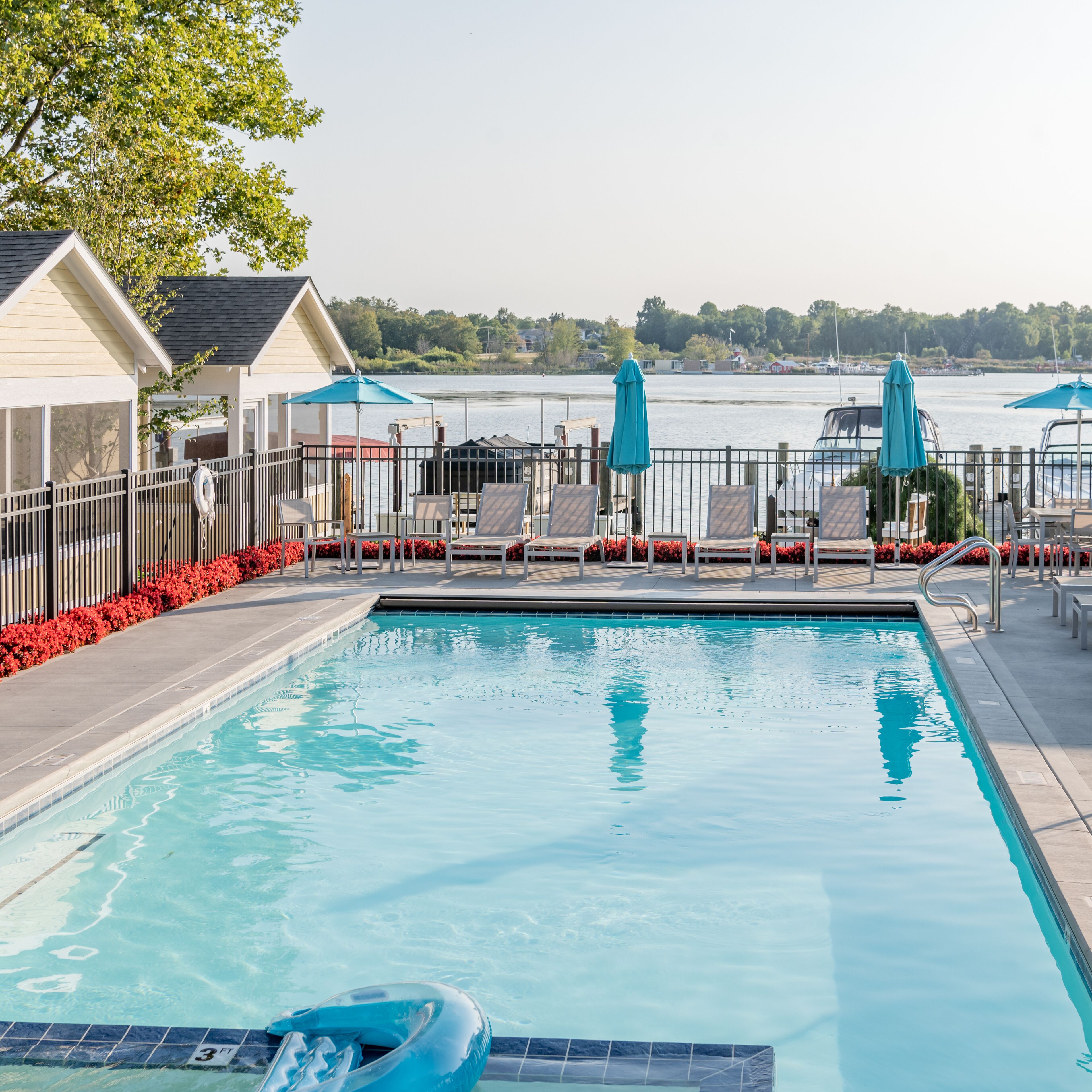 A swimming pool with a view of the water and boats in the background.