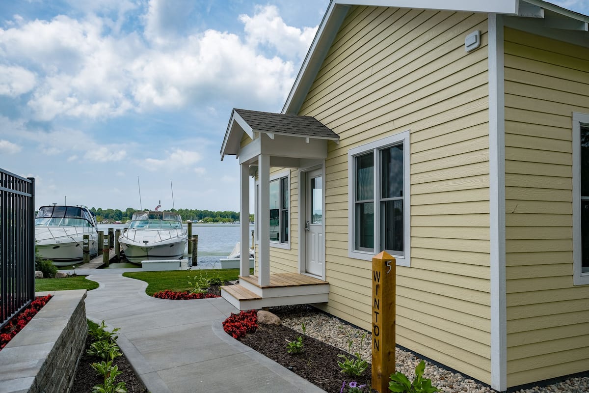 A house with a covered porch, a dock with boats, and a view of the water.