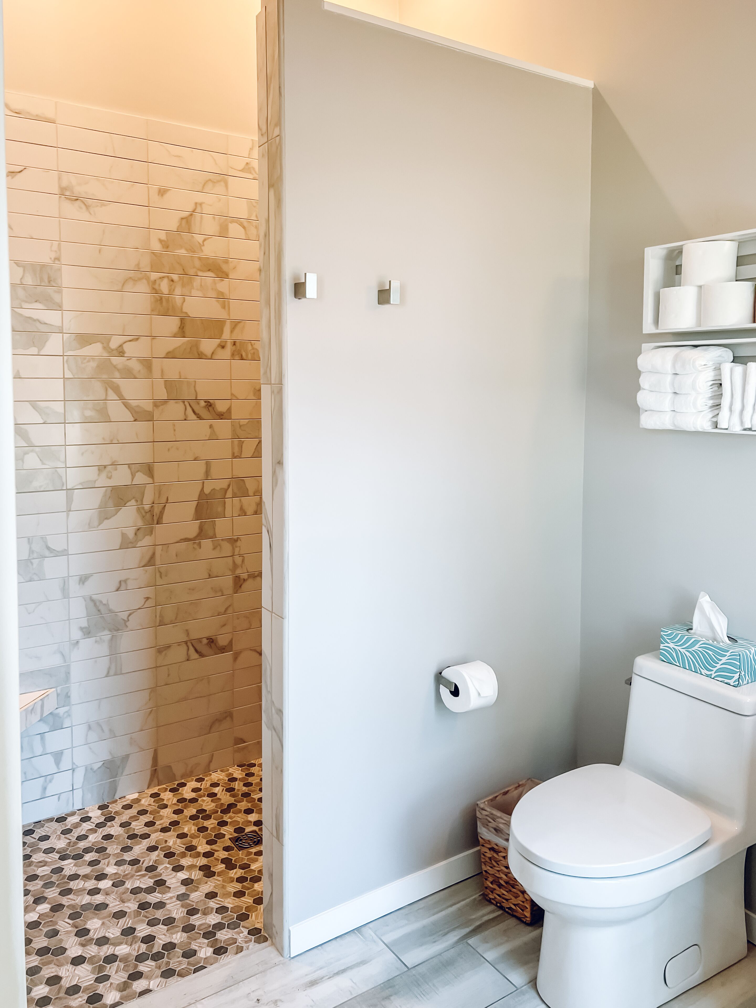 Un baño con ducha, inodoro y estanterías.