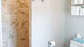 Un baño con ducha, inodoro y estanterías.