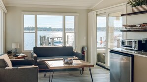 A modern kitchen with a dining area, large windows with a view of the water, and a built-in dishwasher. - Old Pike Cottages (Saugatuck)