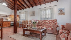A living room with a wooden coffee table, floral sofa, and a kitchen in the background. - Villa "Abraham" with Mountain View, Wi-Fi, Pool & Terrace (Tefía)