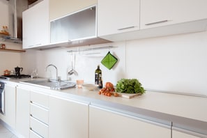 A modern kitchen with white cabinets, a stainless steel sink, and a countertop with various kitchen items.