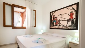 Ein Hotelzimmer mit einem Bett, einem Nachttisch, einer Lampe, einem Bild und einem Fenster mit Vorhängen.
