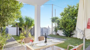 An outdoor patio with a table set for dining, surrounded by wicker chairs and potted plants.