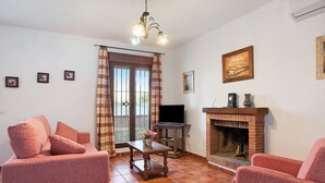 A living room with a sofa, a table with a vase, a fireplace, and a television.