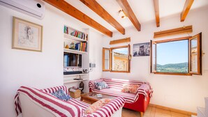 Una sala de estar acogedora con un sofá, una estantería, un ventanal con vistas y un techo de madera.