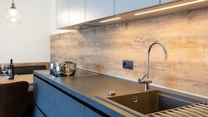 A modern kitchen with a wooden backsplash, stainless steel appliances, and a sleek countertop. - Holiday Apartment "Wohnung 5" with Sauna, Terrace & Mountain View (Terenten)