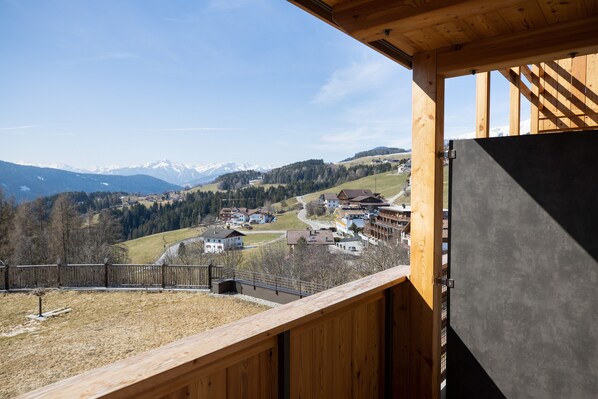 Ein Holzbalkon mit Blick auf ein Dorf und Berge.