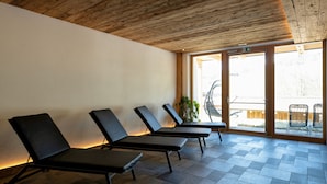 A room with wooden ceiling, large windows, and three black lounge chairs. - Holiday Apartment "Wohnung 5" with Sauna, Terrace & Mountain View (Terenten)