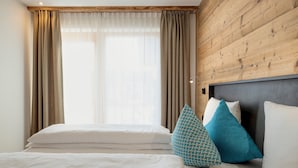 A hotel room with a bed, two pillows, a wooden headboard, and a window with curtains. - Holiday Apartment "Wohnung 5" with Sauna, Terrace & Mountain View (Terenten)