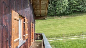 A wooden building with a brick pathway leading to a balcony overlooking a grassy field. - Vacation on a Farm - Fantastic Holiday App with Balcony, Garden, Lake & Mountain View (Schliersee)