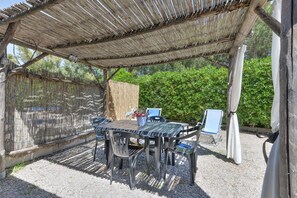 Un espacio al aire libre cubierto con una mesa y sillas, rodeado por una cerca de madera y follaje.