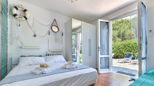 A bedroom with a bed, a bathroom, and a view of the outdoors. - Modern apartment with garden, air conditioning and Wi-Fi (LACONA - CAPOLIVERI (LIVORNO))