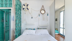 A bedroom with a bed, a mirror, a life preserver, and a window. - Modern apartment with garden, air conditioning and Wi-Fi (LACONA - CAPOLIVERI (LIVORNO))