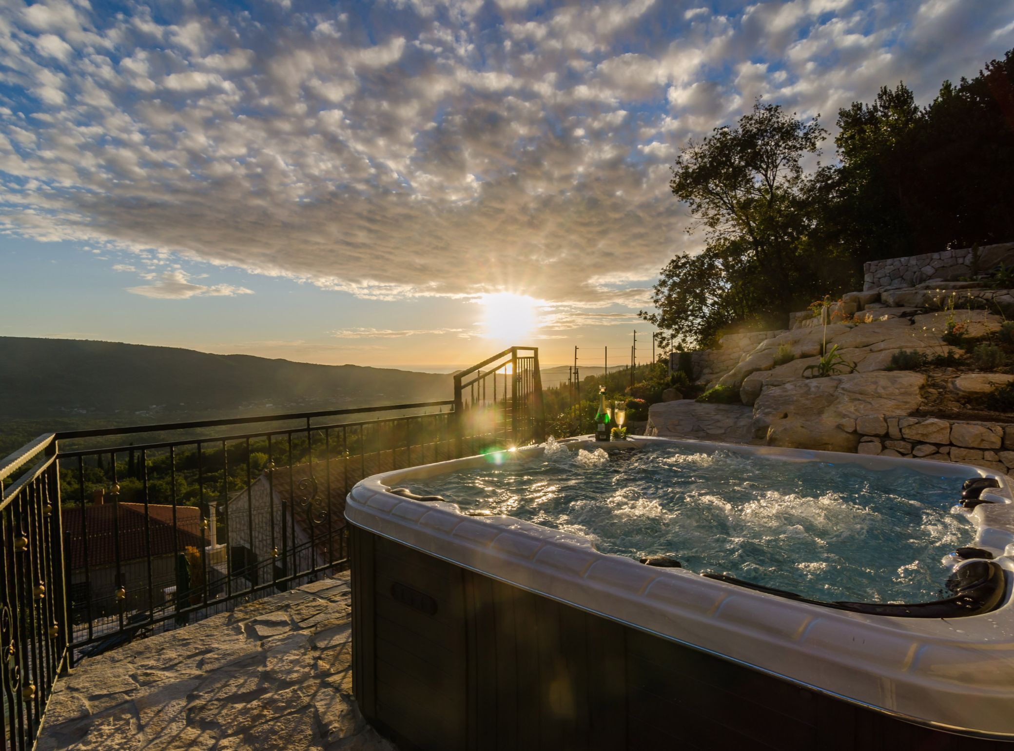 A hot tub with a scenic view of the sunset and mountains.